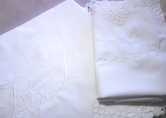 sábanas blancas con puntilla y bordadas con iniciales en blanco