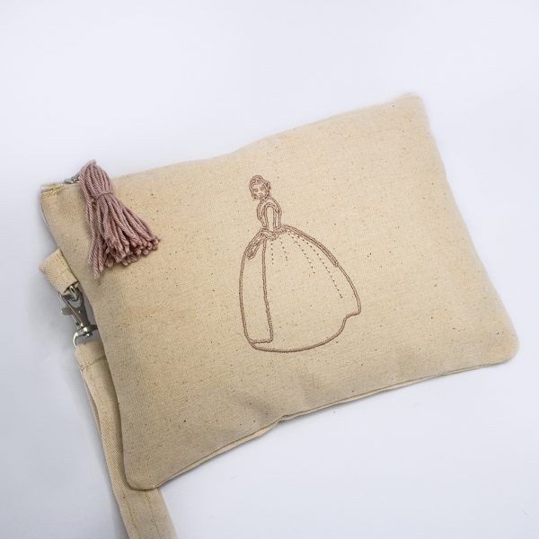 cartera de color beige con bordado castellonera y pompón en color rosa empolvado
