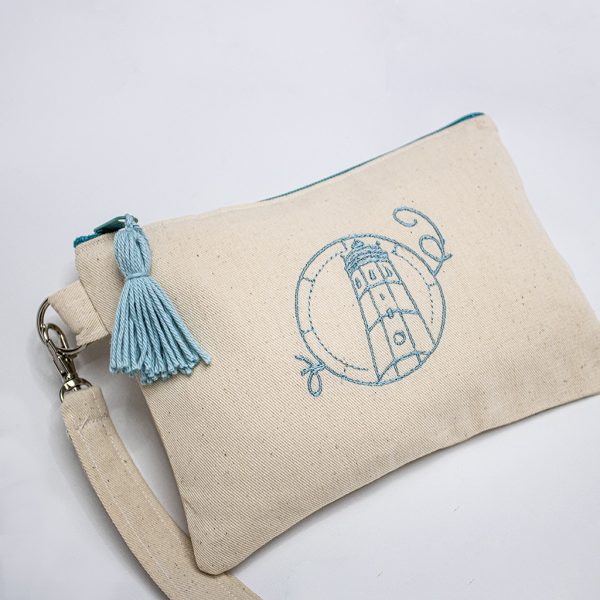 cartera magdalenera con dibujo bordado en azul claro del fardo y combinado con pompón y cremallera en el mismo color azul claro