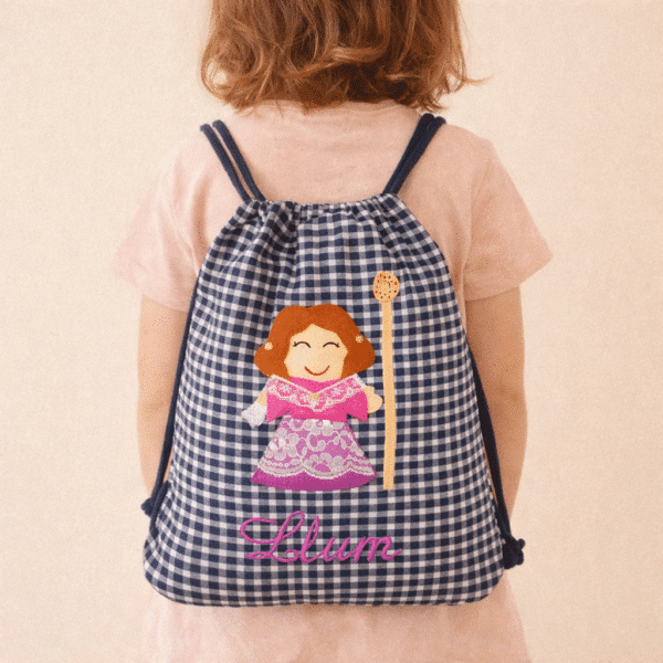 niña pequeña con mochila artesanal en espalda a cuadros blancos y azul con castellonera