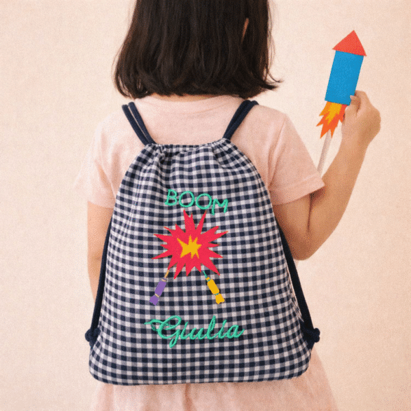 niña con mochila cohetes bordados y cohete de cartón de juguete en la mano
